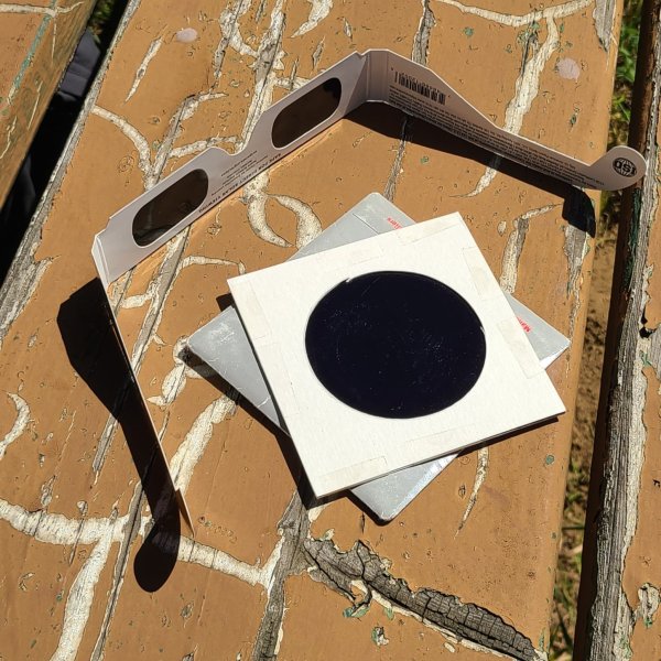 Eclipse glasses and a filter on a picnic table © Joan Schipper