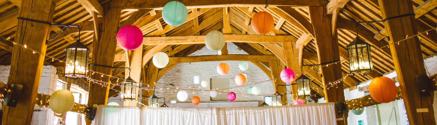 Lanterns hang from a barn style venue by Tom Pumford via Unsplash