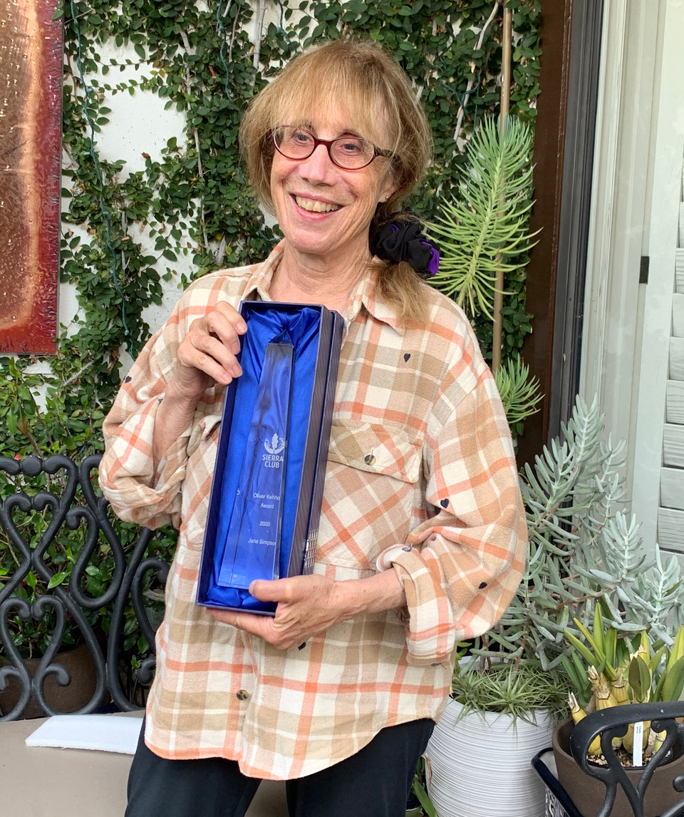 Jane Simpson poses with award outside of her home