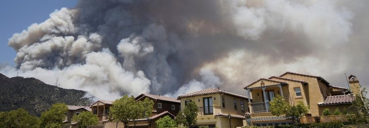 Smoke from one of two wildfires in the Angeles National Forest rises above homes in Azusa, CA